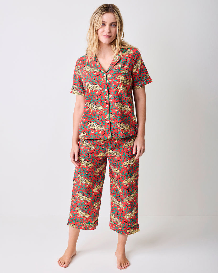 Front view of a person wearing the red Winter Holly Bagheera pajama set with a short-sleeve button-down top and cropped pants.