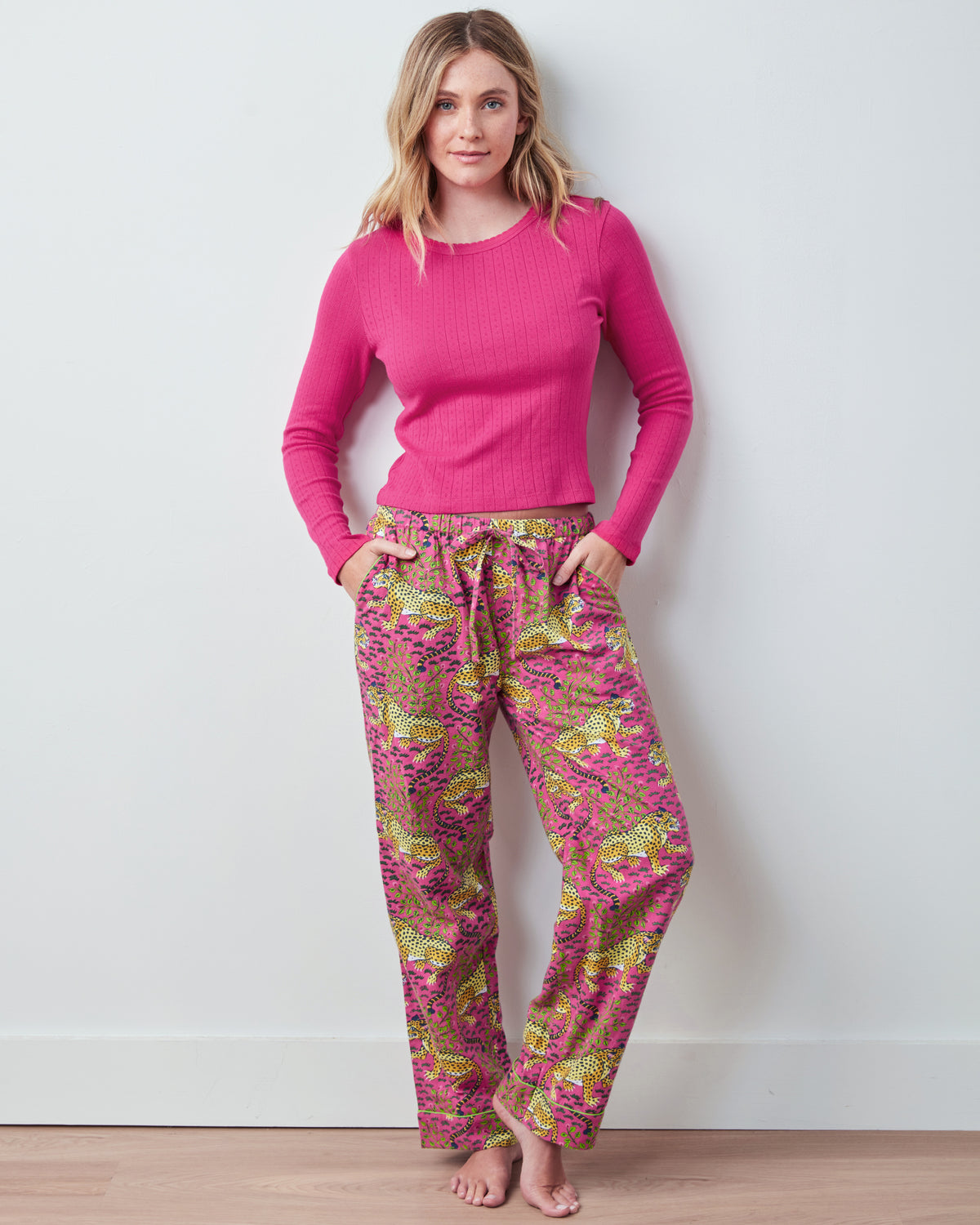 Bright pink long-sleeve pointelle shirt shown in a full-body front view with patterned pants