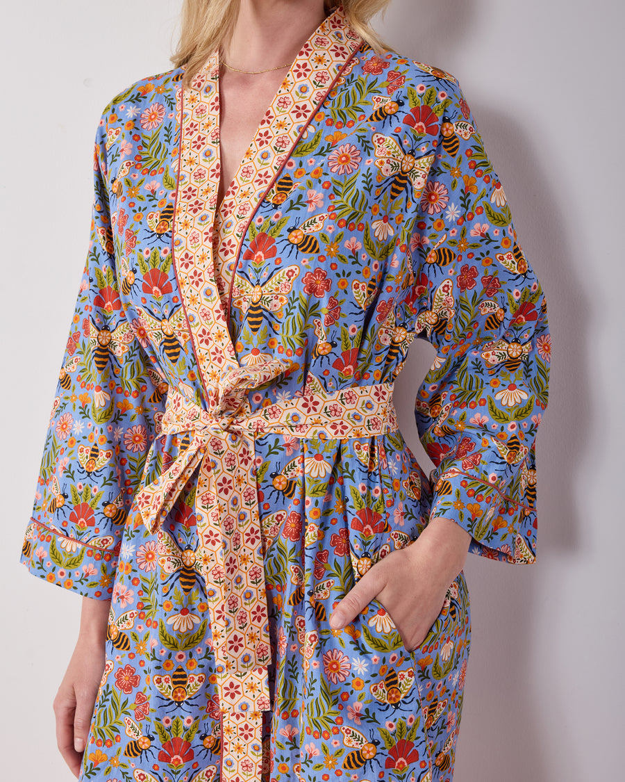 Close front view of the Delphinium Blue Bee Tapestry robe showing the shawl collar, tied belt, pocket, and sleeve trim.