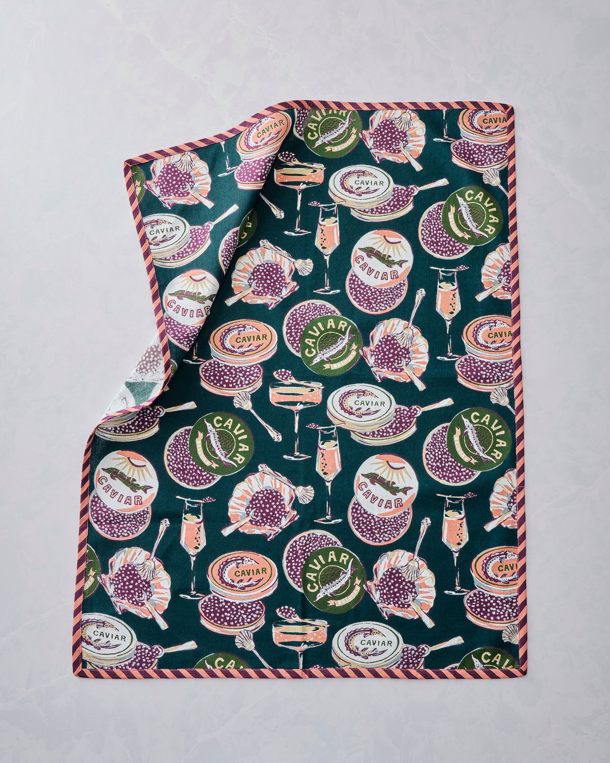 Champagne & Caviar tea towel laid flat with a repeating teal print of caviar tins, champagne glasses, and seafood motifs.