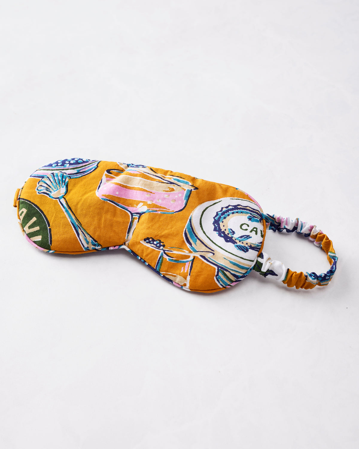 Champagne & Caviar eye mask in Goldenrod, shown flat with an adjustable elastic strap and illustrated drinkware and caviar motifs.