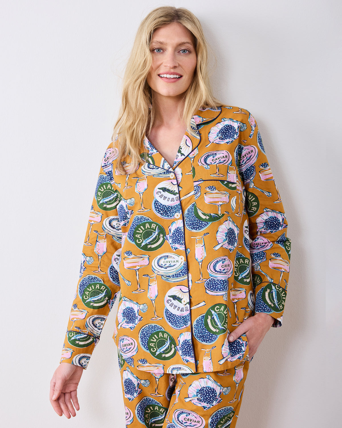 Front detail of the goldenrod Champagne & Caviar pajama set, showing the button-front top, collar, pocket, and printed pants.