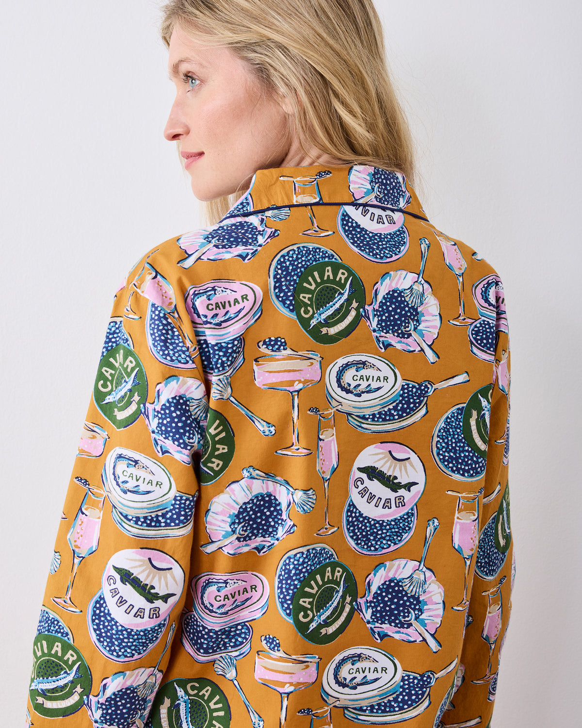Close back view of the goldenrod Champagne & Caviar pajama top, showing the collar, long sleeves, and repeated print.
