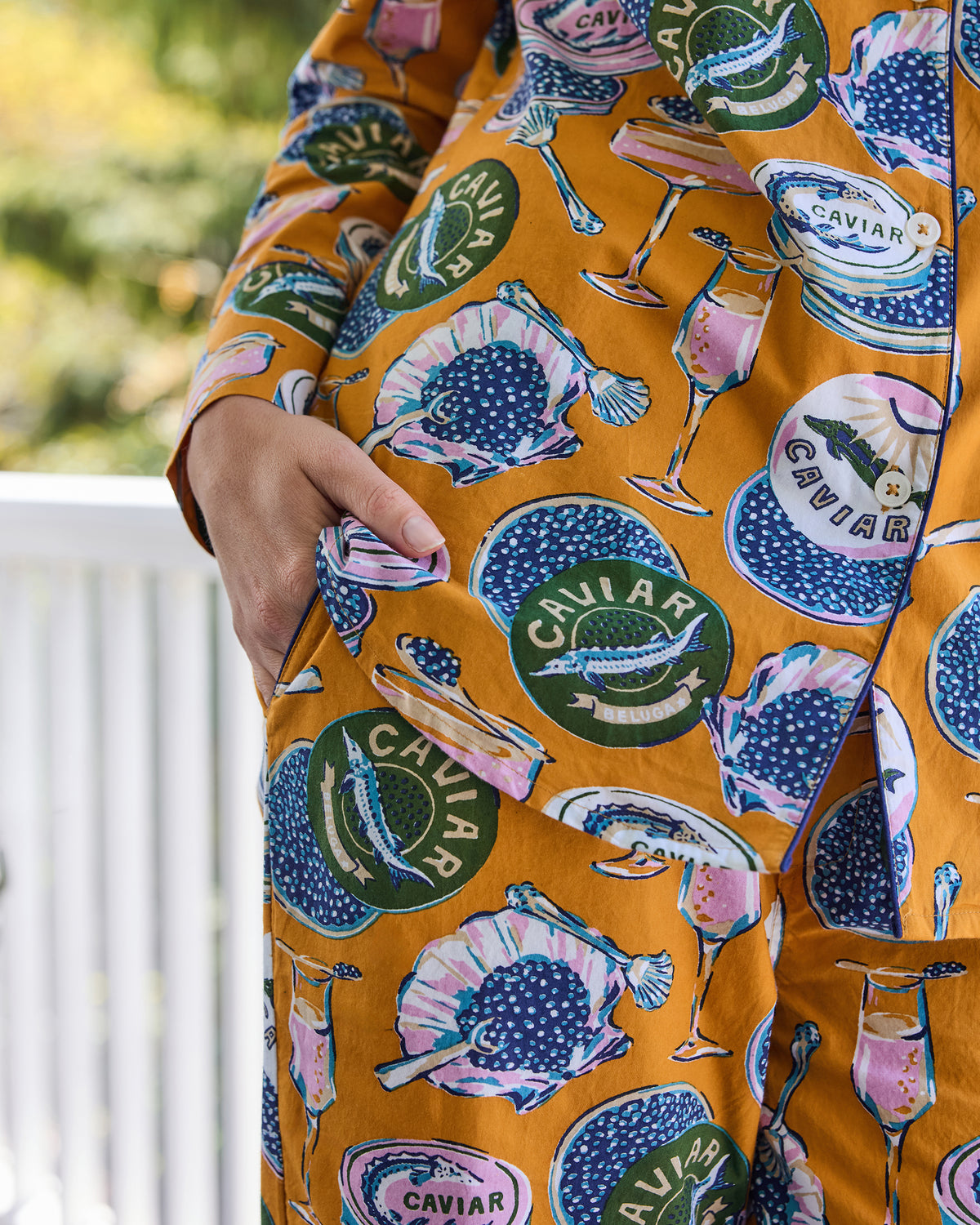 Close-up of the Champagne & Caviar pajama set showing its goldenrod caviar, bowl, and champagne-glass print and a side pocket.