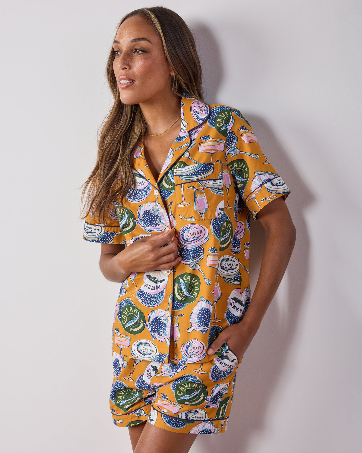 Angled front view of the goldenrod Champagne and Caviar short pajama set with a collared button-front top, chest pocket, and matching shorts.