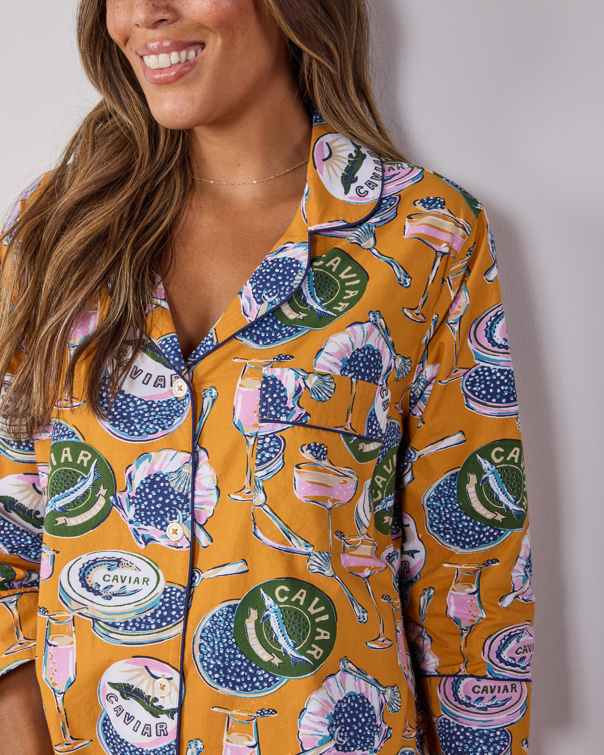Close-up of the Champagne & Caviar sleep shirt showing its collar, buttons, chest pocket, and printed caviar motifs.