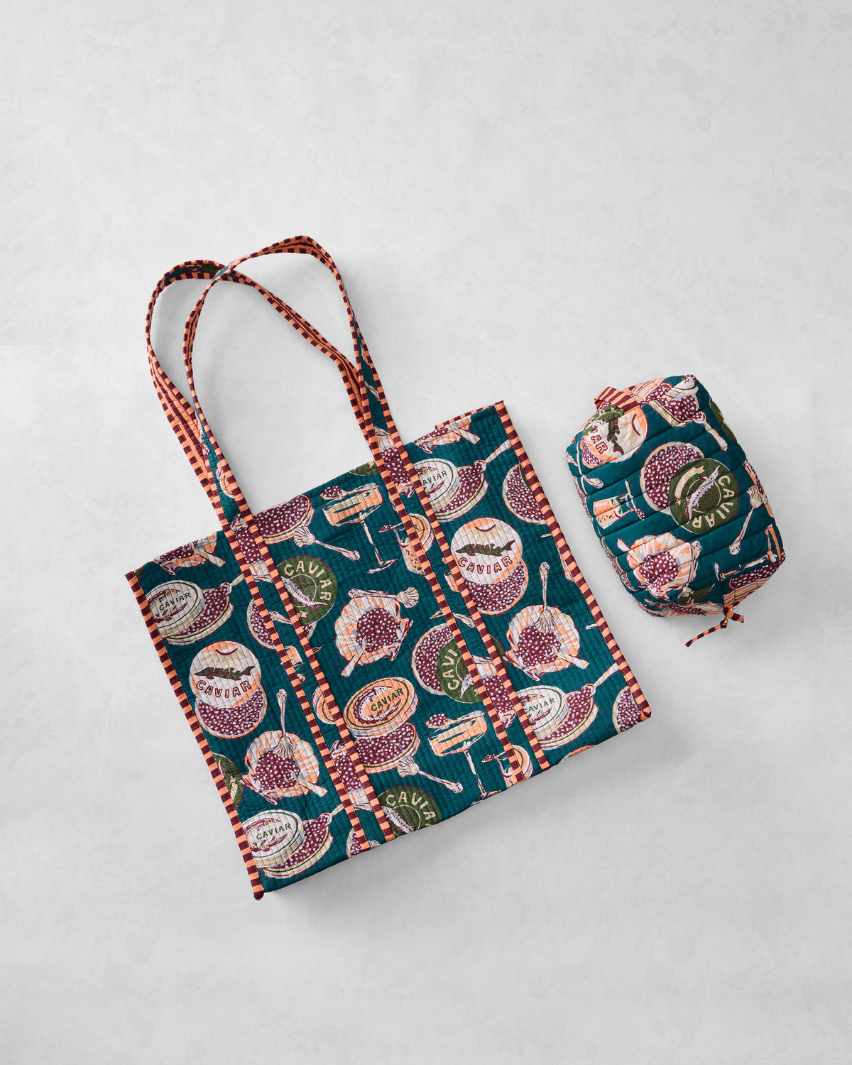 Flat lay of the Champagne & Caviar Traveler Tote and Quilted Pouch Bundle in Peacock Feather print, showing the tote and matching quilted pouch.