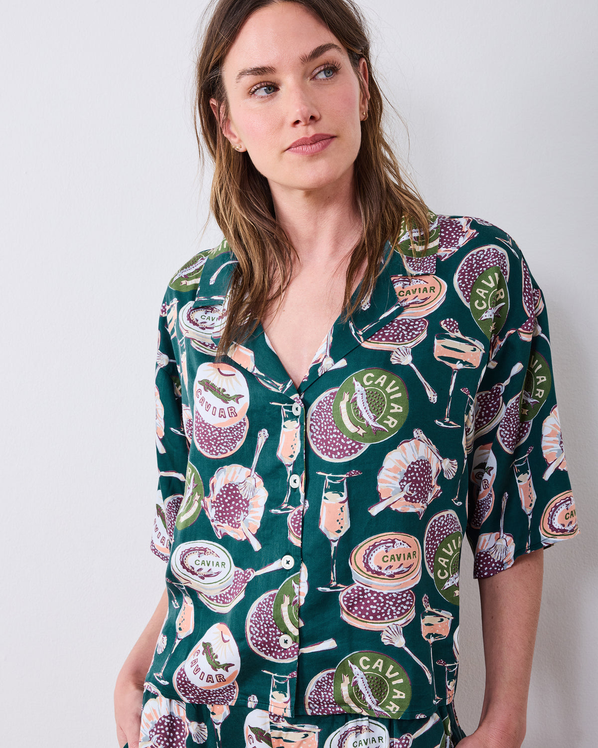 Close front view of the tall Champagne & Caviar Wildest Dreams pajama top with short sleeves, buttons, and a caviar-and-champagne print.