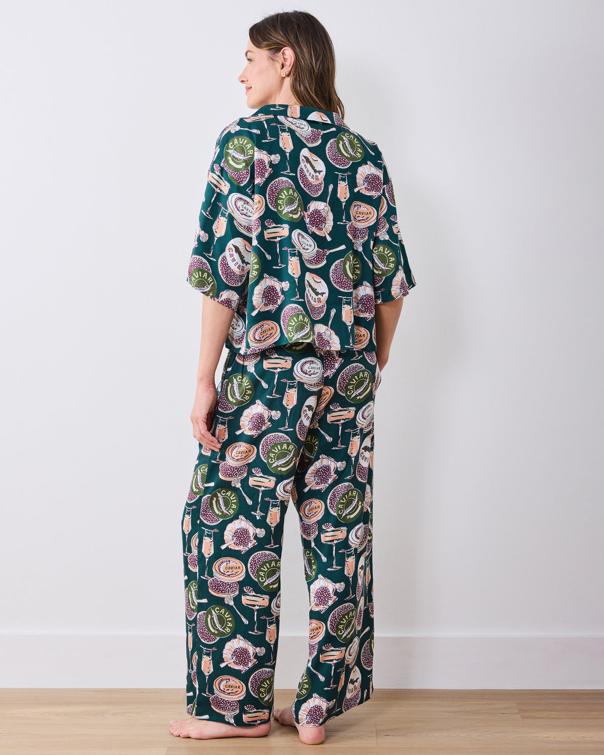 Back view of a person wearing the Champagne & Caviar pajama set, showing the loose short-sleeved top and wide-leg printed pants.