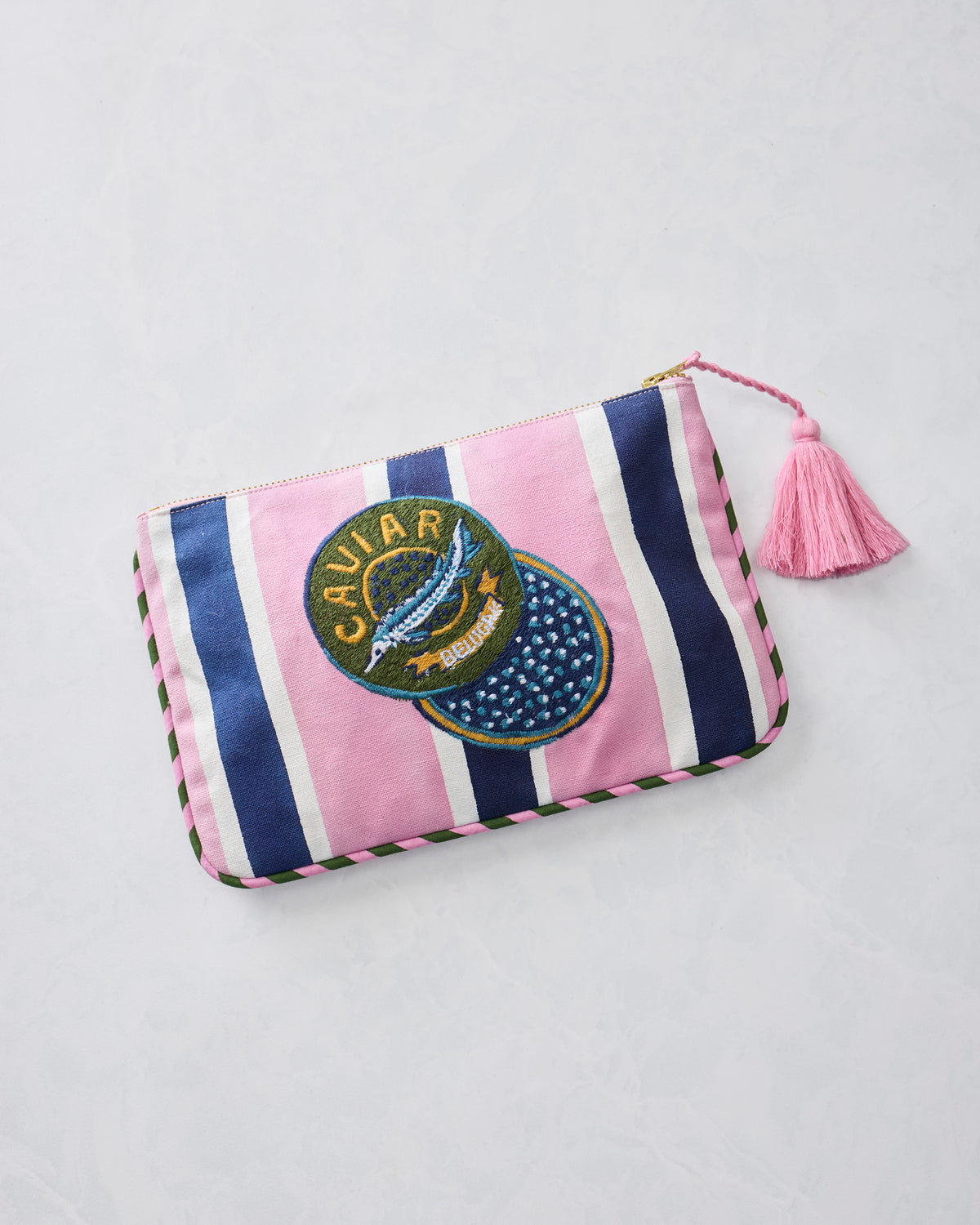 Harbor Rose striped canvas pouch shown at an angle with an embroidered CAVIAR patch, zipper closure, and pink tassel.
