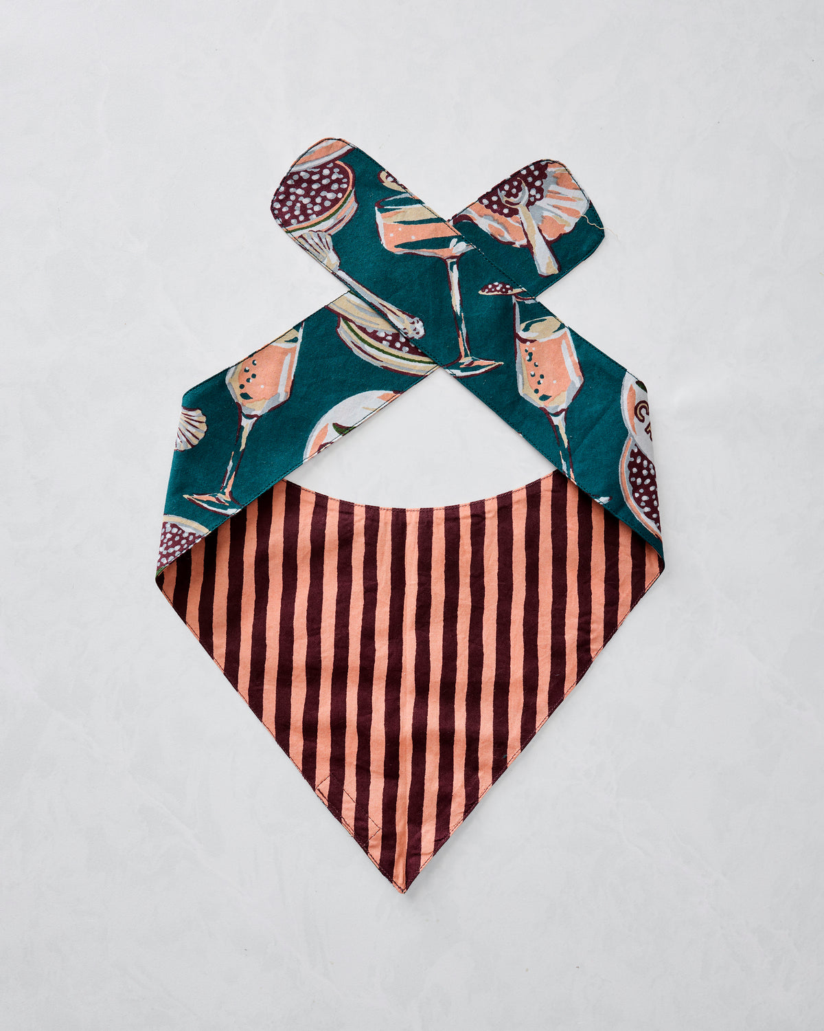Reverse side of a Champagne & Caviar pet bandana with a pink-and-brown striped body and teal printed tie straps.