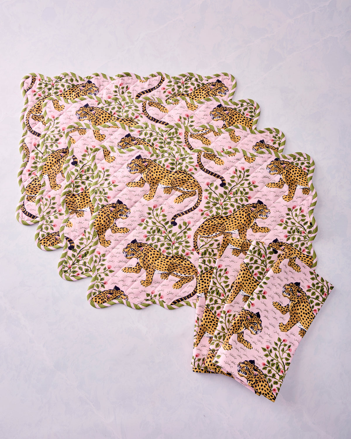 Four scalloped placemats and four folded napkins arranged to show the leopard and floral print