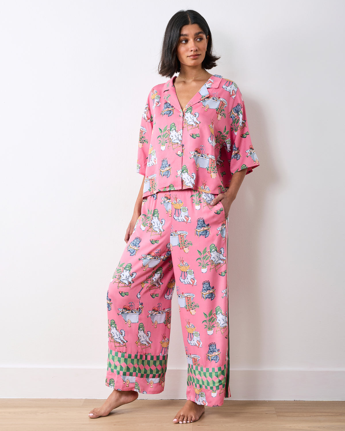 Model wearing a pink cropped pajama top and wide-leg pants with a cat spa-day print and patterned cuffs.