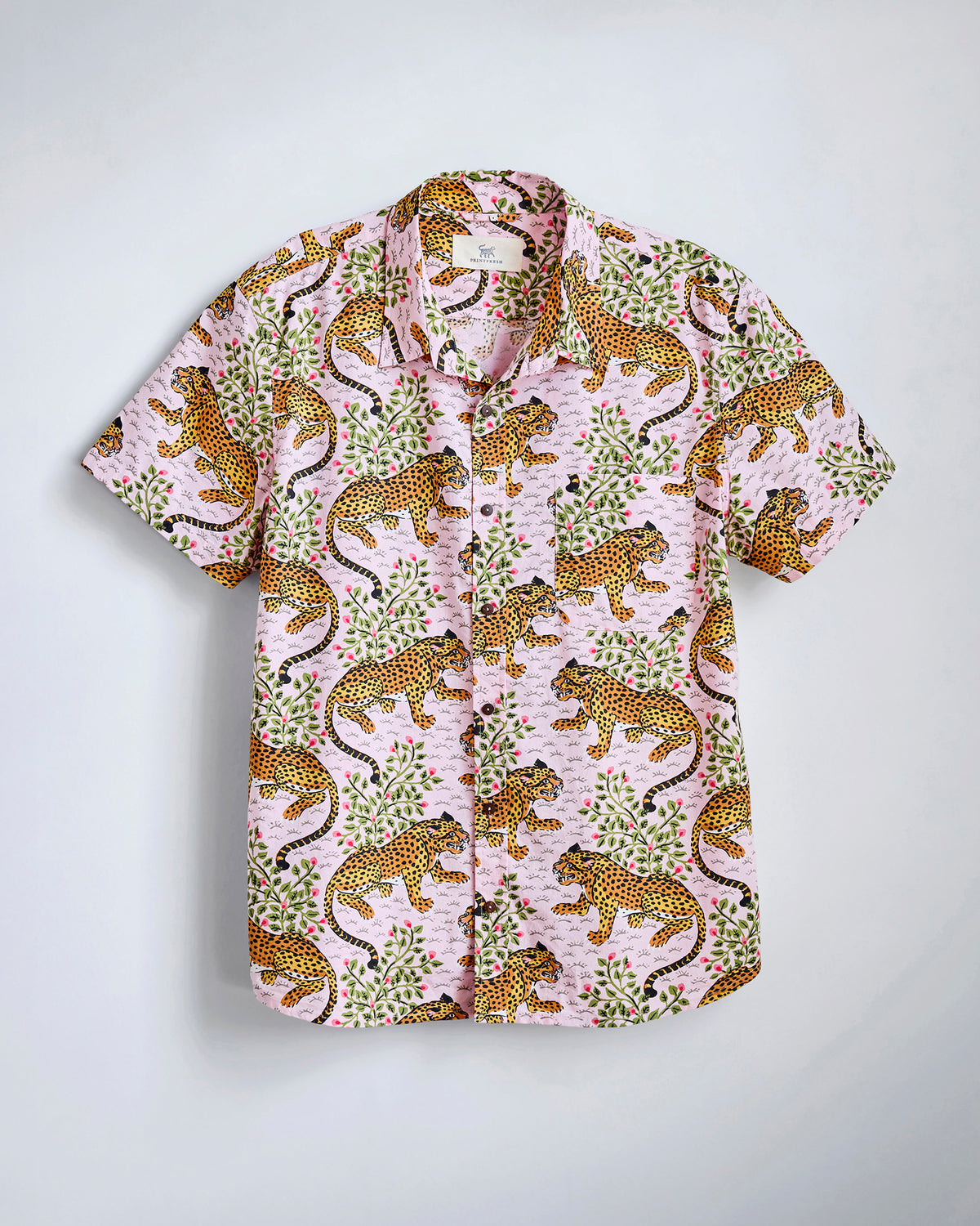Flat-lay of the blush Bagheera Leo Shirt with an orange leopard-and-floral print, short sleeves, collar, chest pocket, and button front.
