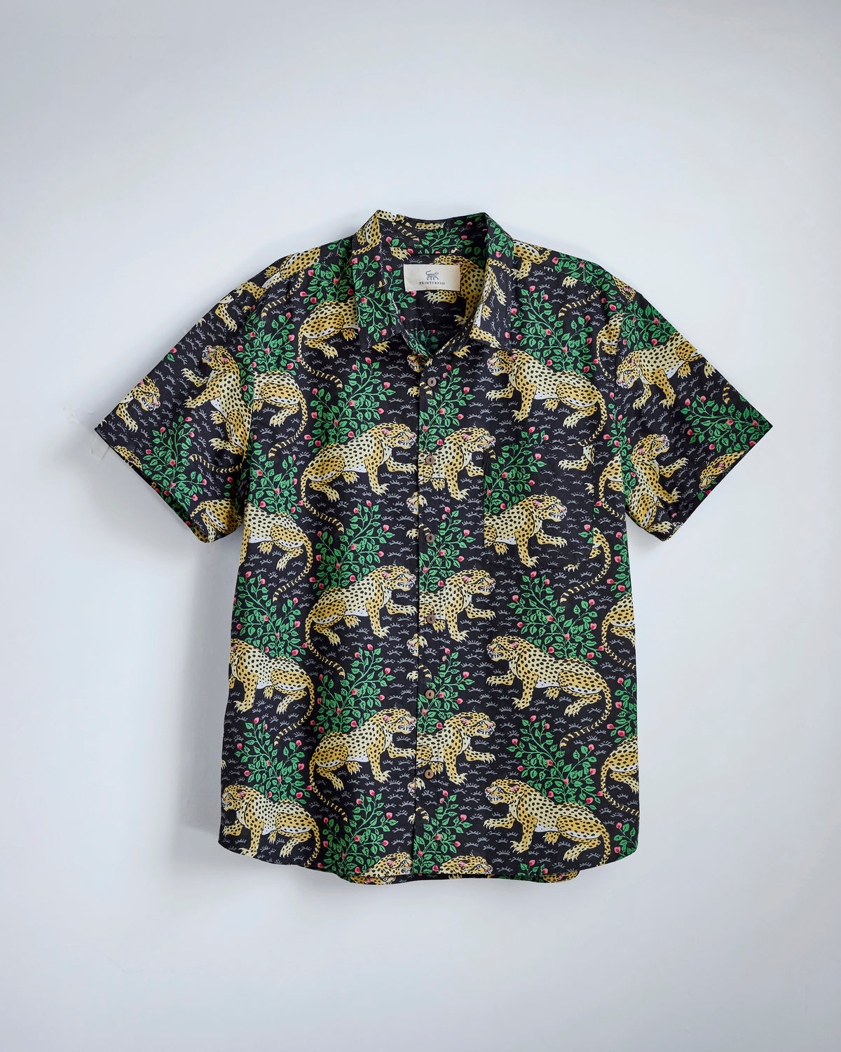 Flat-lay of the Ink Bagheera Leo Shirt with a leopard-and-green foliage print, short sleeves, collar, chest pocket, and button front.