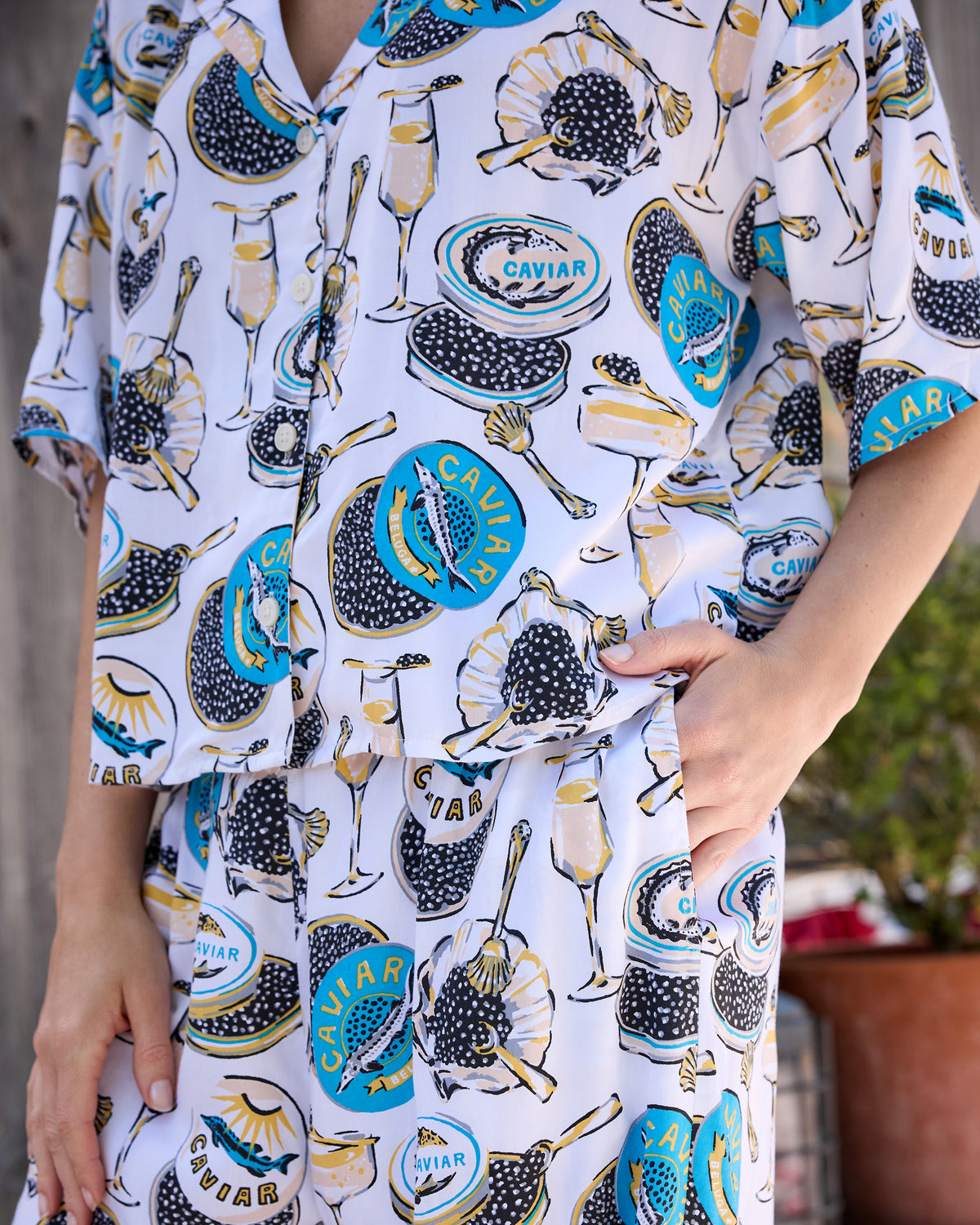 Close view of the pajama top and high-rise pants, showing the printed design and a hand inside the pants pocket.