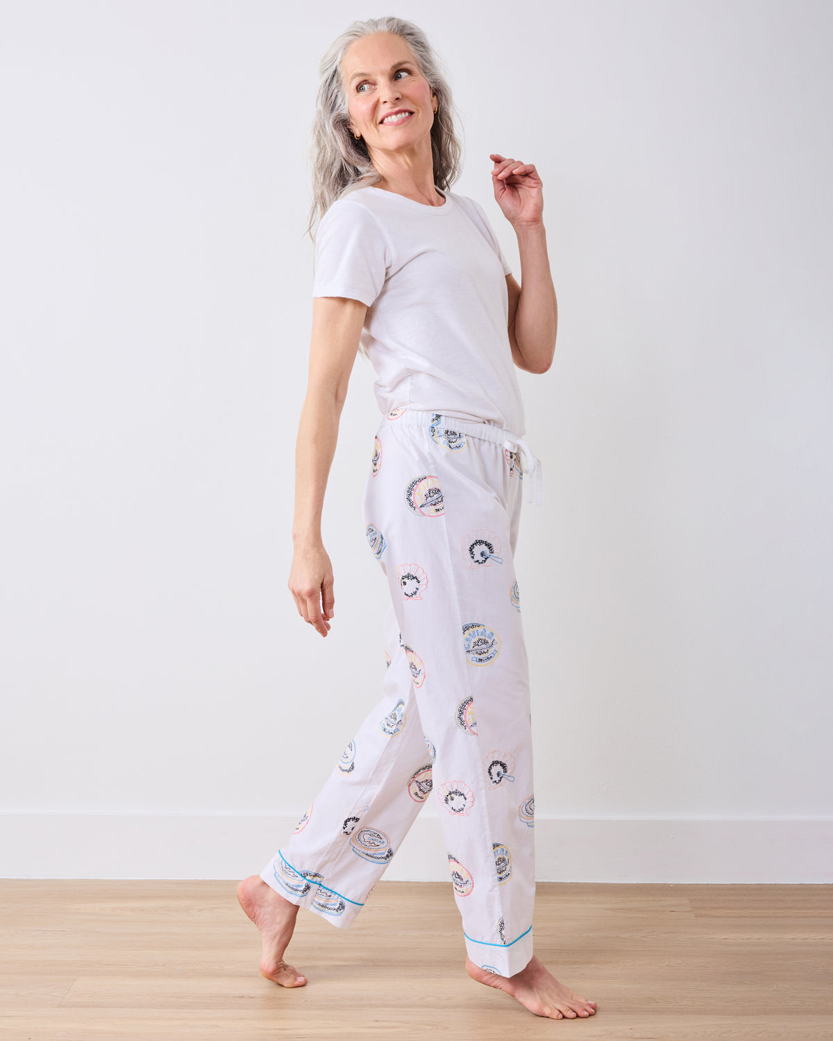 Side view of the Embroidered Caviar Club pajama pants with an elastic drawstring waist, blue-piped cuffs, and embroidered motifs.