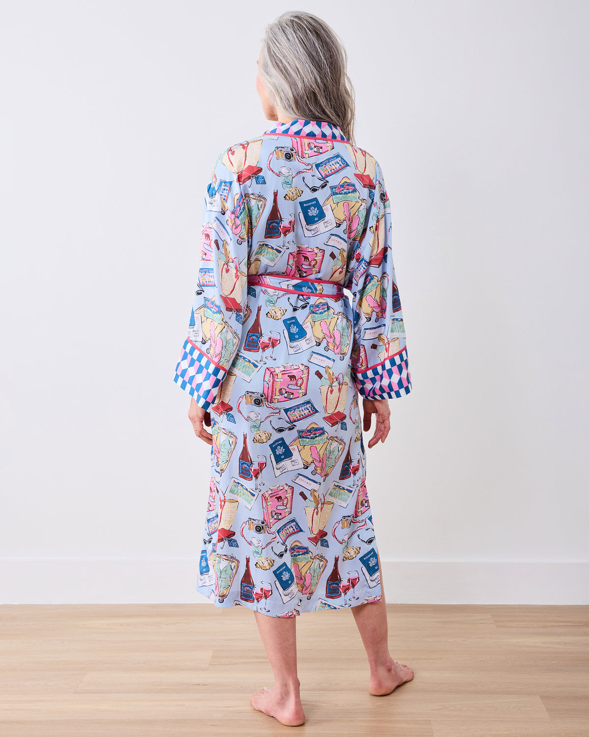 Back view of a person wearing a full-length pale blue printed robe with a matching belt and patterned cuffs.