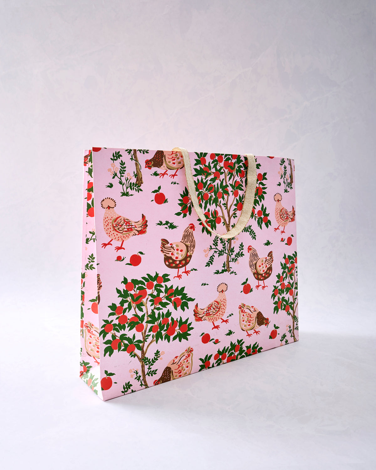 Pink gift bag printed with chickens, apple trees, and scattered apples