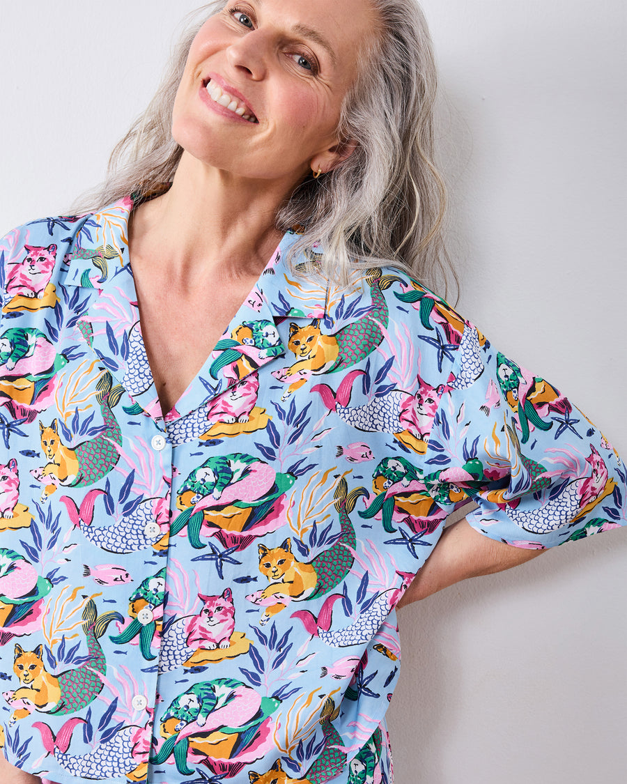 Close front view of the pale blue pajama top with a cat-mermaid and underwater print