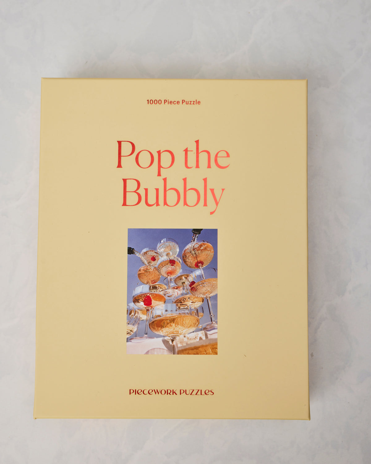Front of the Pop the Bubbly 1000-piece puzzle box, showing champagne coupes with cherries.