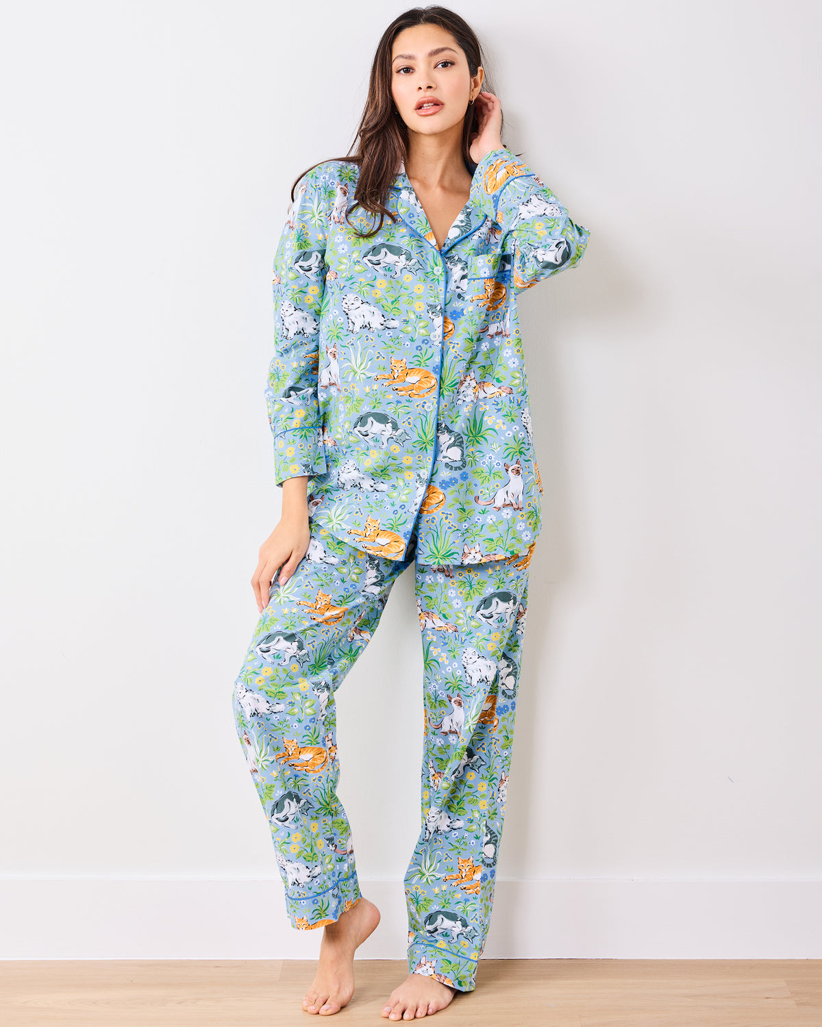 Full front view of a model wearing the blue long pajama set with cats, flowers, and greenery