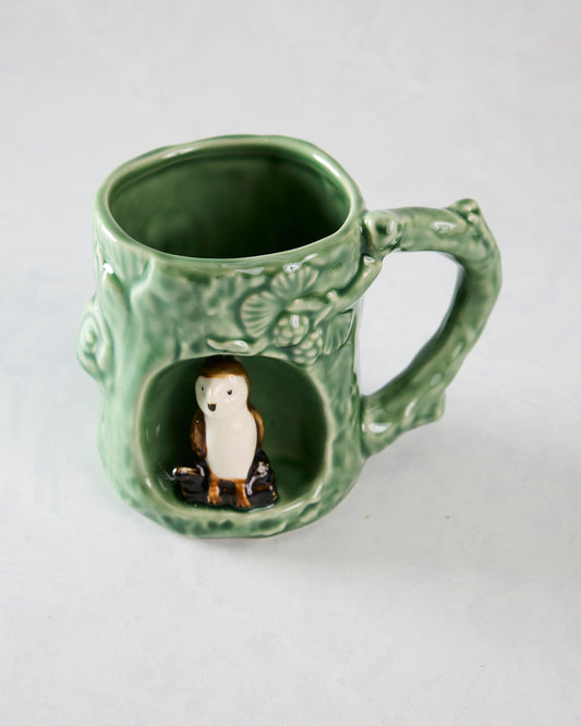 Green textured mug with a handle, raised woodland details, and a barn owl figurine in the front alcove.