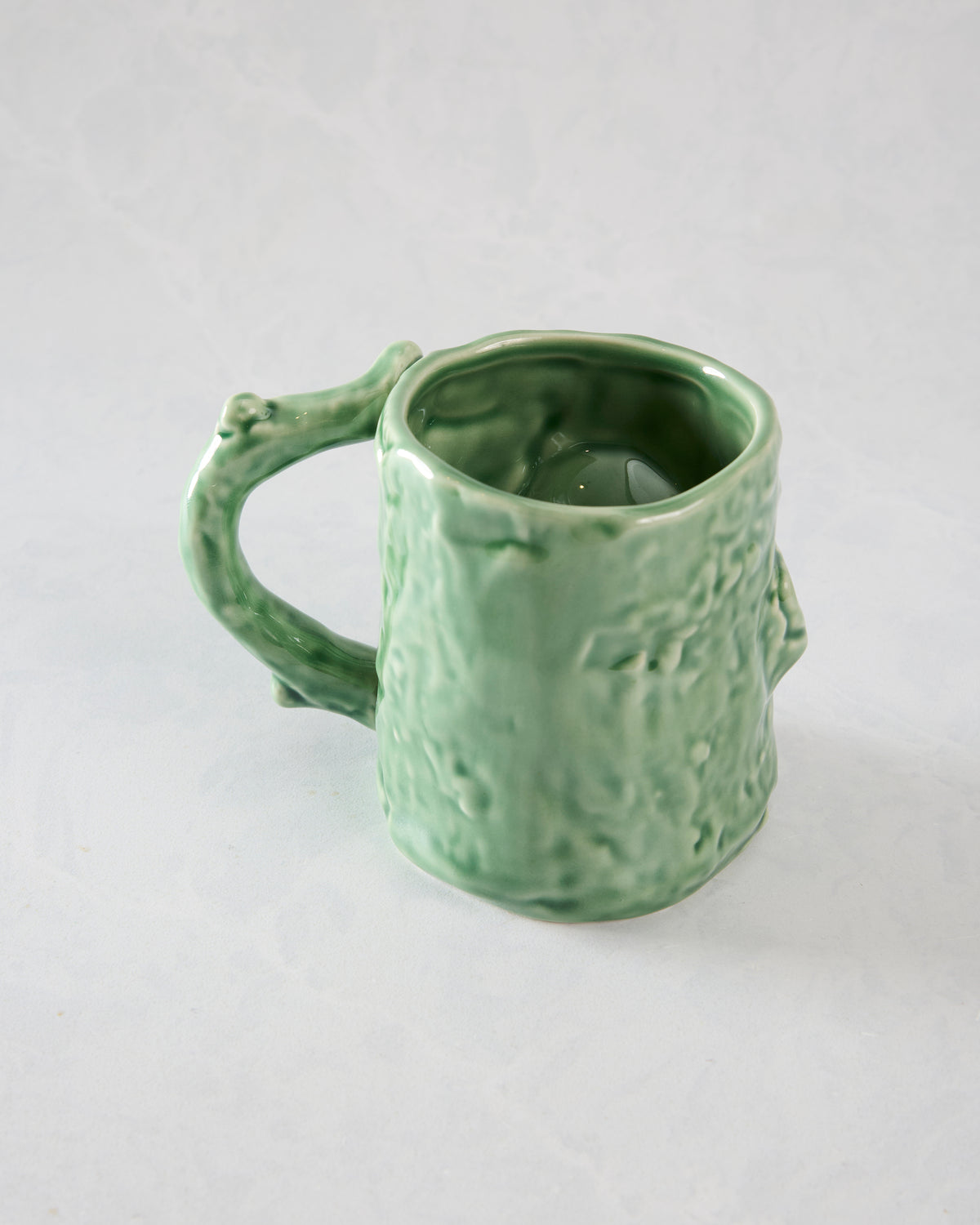 Back view of the green textured mug showing its handle, raised surface details, and open interior.