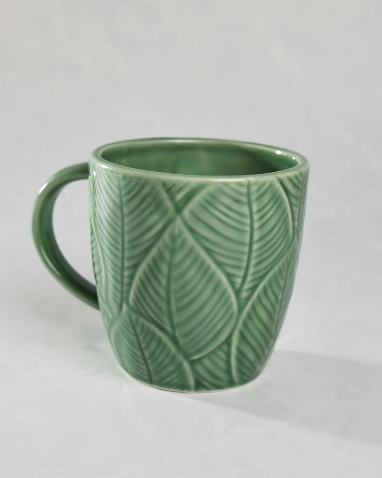 Green leaf-patterned mug shown from the back with an empty interior and handle on the left.