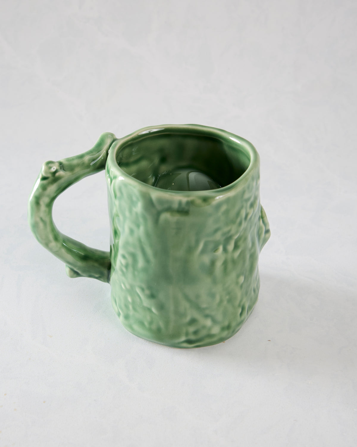 Green textured mug shown from the side with a curved handle and open top.