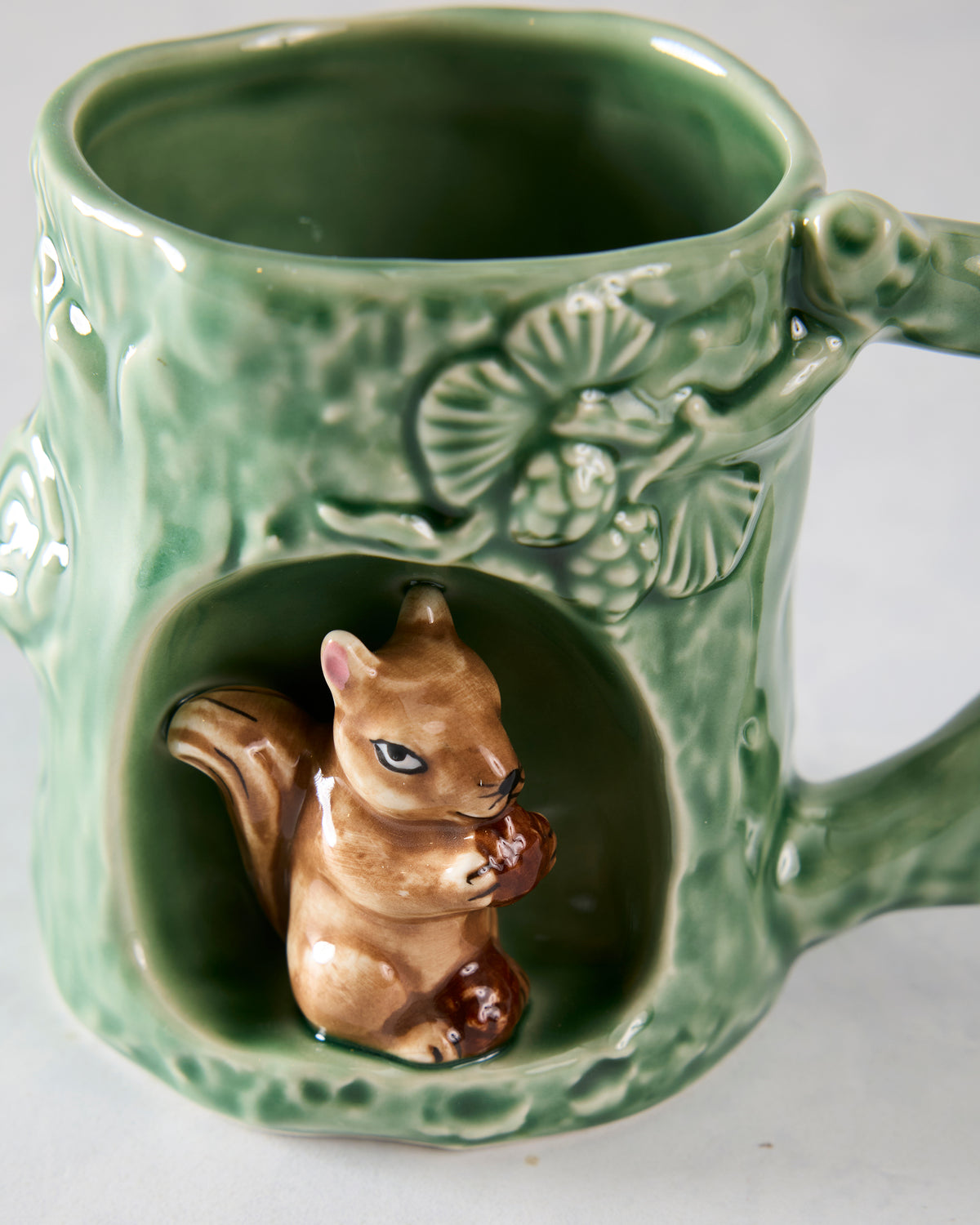 Close-up of the green squirrel mug showing a squirrel figurine inside a front alcove and raised floral detailing.