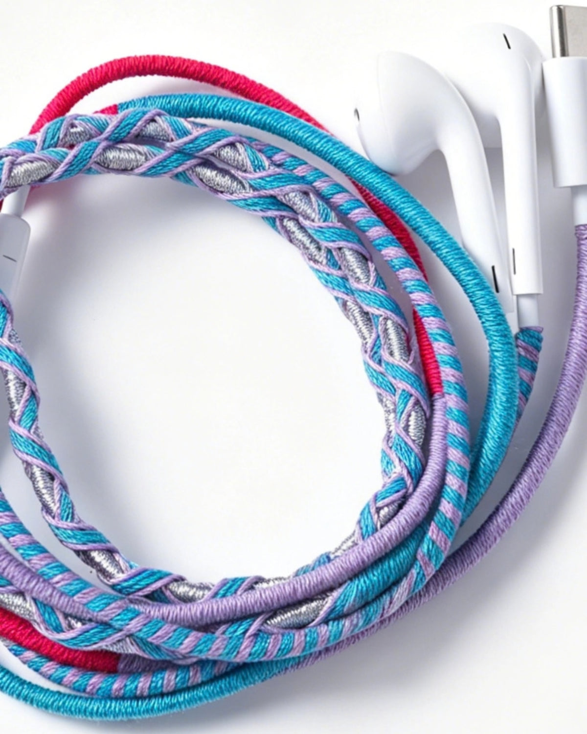 Close-up of wired in-ear headphones with braided multicolor cables and white earbuds.