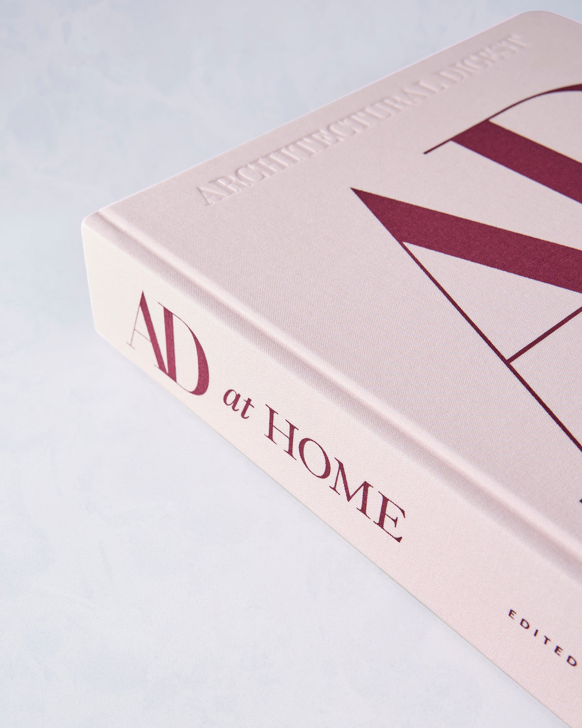 Close-up of the pale pink spine and cover of the AD at Home book, with the title and Architectural Digest lettering visible.