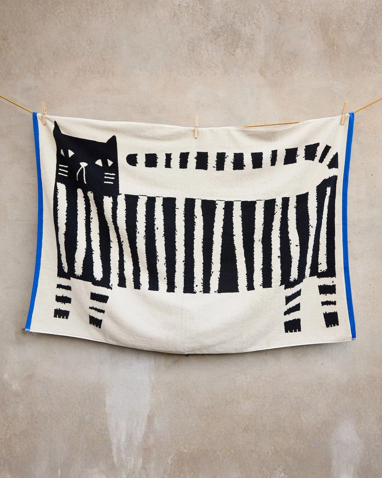 Lazy Cat XL sheet towel hanging from a clothesline, showing a black cat and piano-key pattern.
