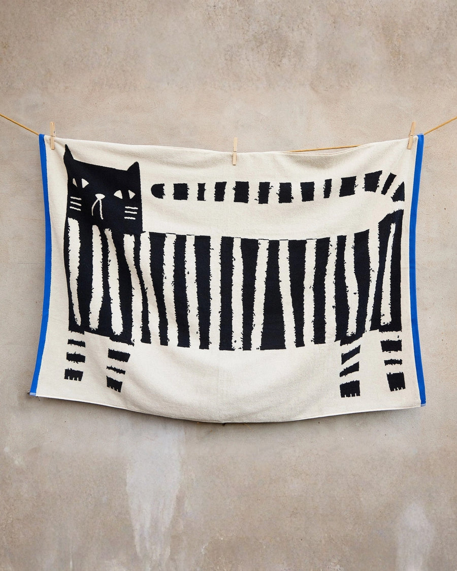 Lazy Cat XL sheet towel hanging from a clothesline, showing a black cat and piano-key pattern.