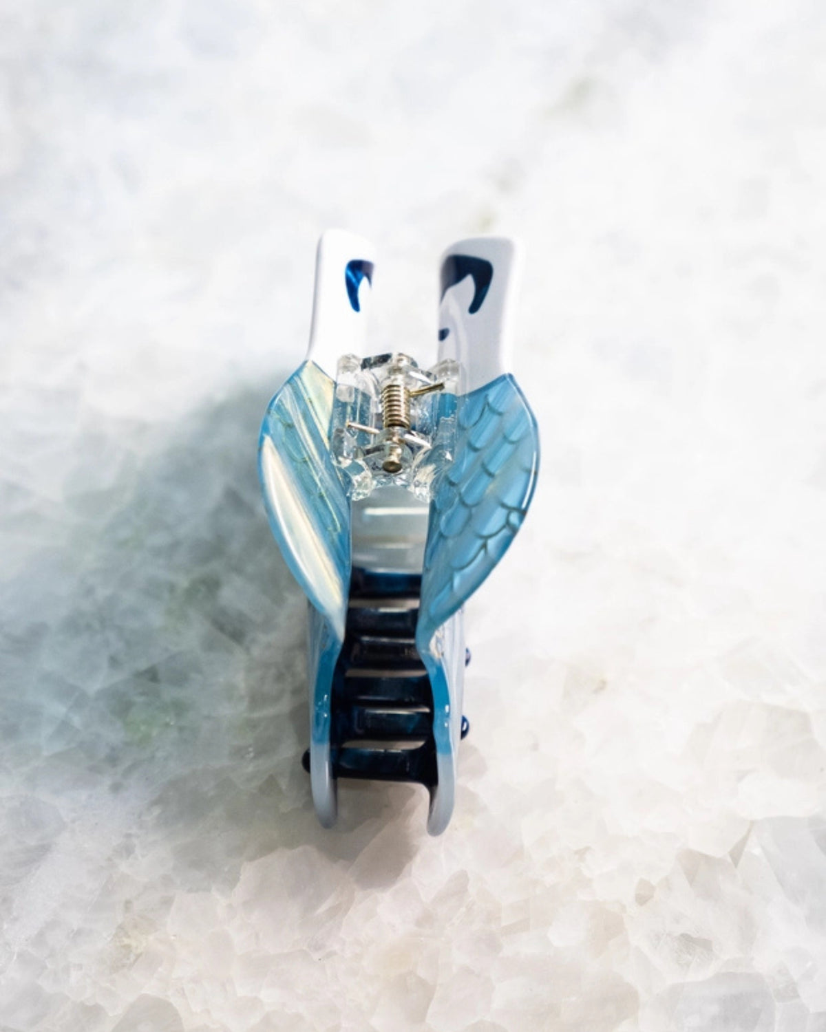 Mermaid-shaped hair clip shown open from the back, with its metal spring mechanism visible