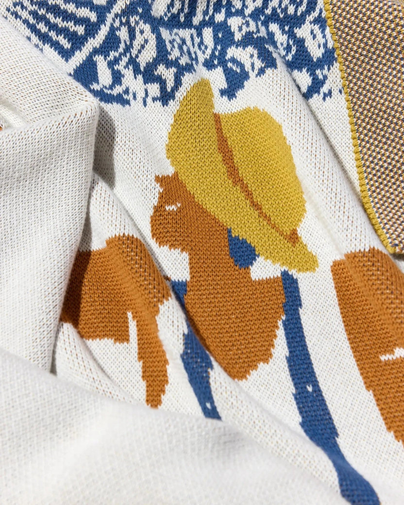 Close-up of the Un Beau Poisson throw showing the figure's yellow hat, face, and patterned knit surface.