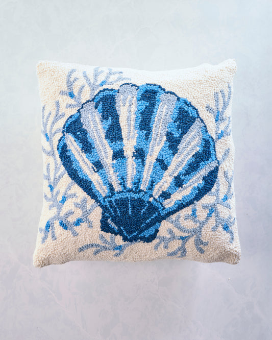 Square accent pillow with a large blue scallop shell design and blue botanical details on a light background.