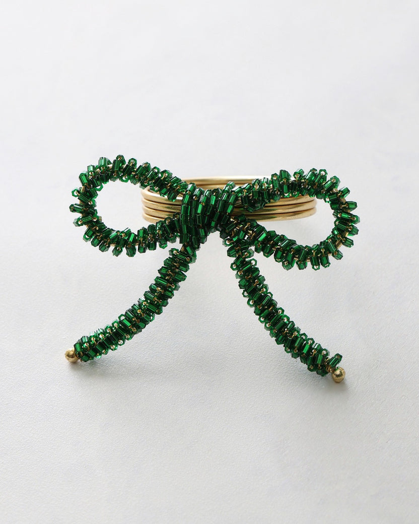 Green beaded bow napkin ring with a gold-tone center and two hanging tails.