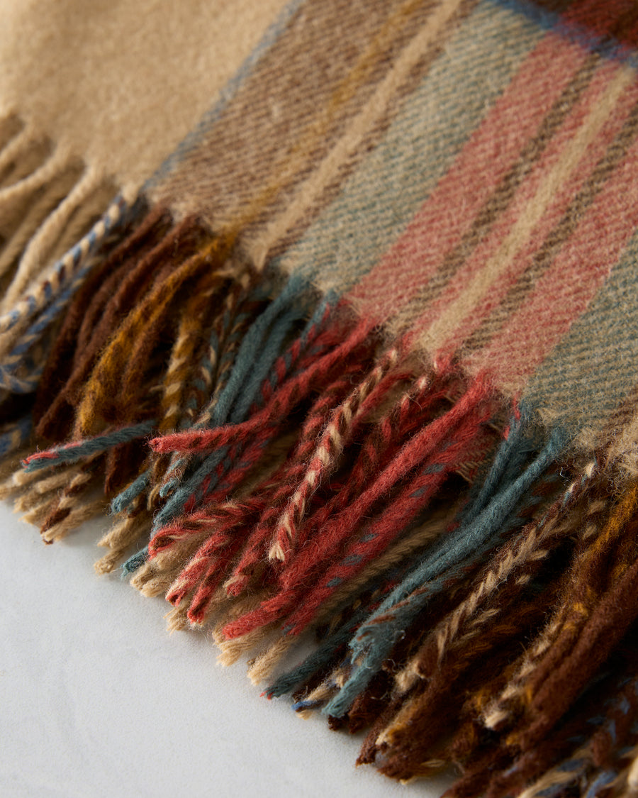 Close-up of the throw’s multicolored fringe and plaid fabric.