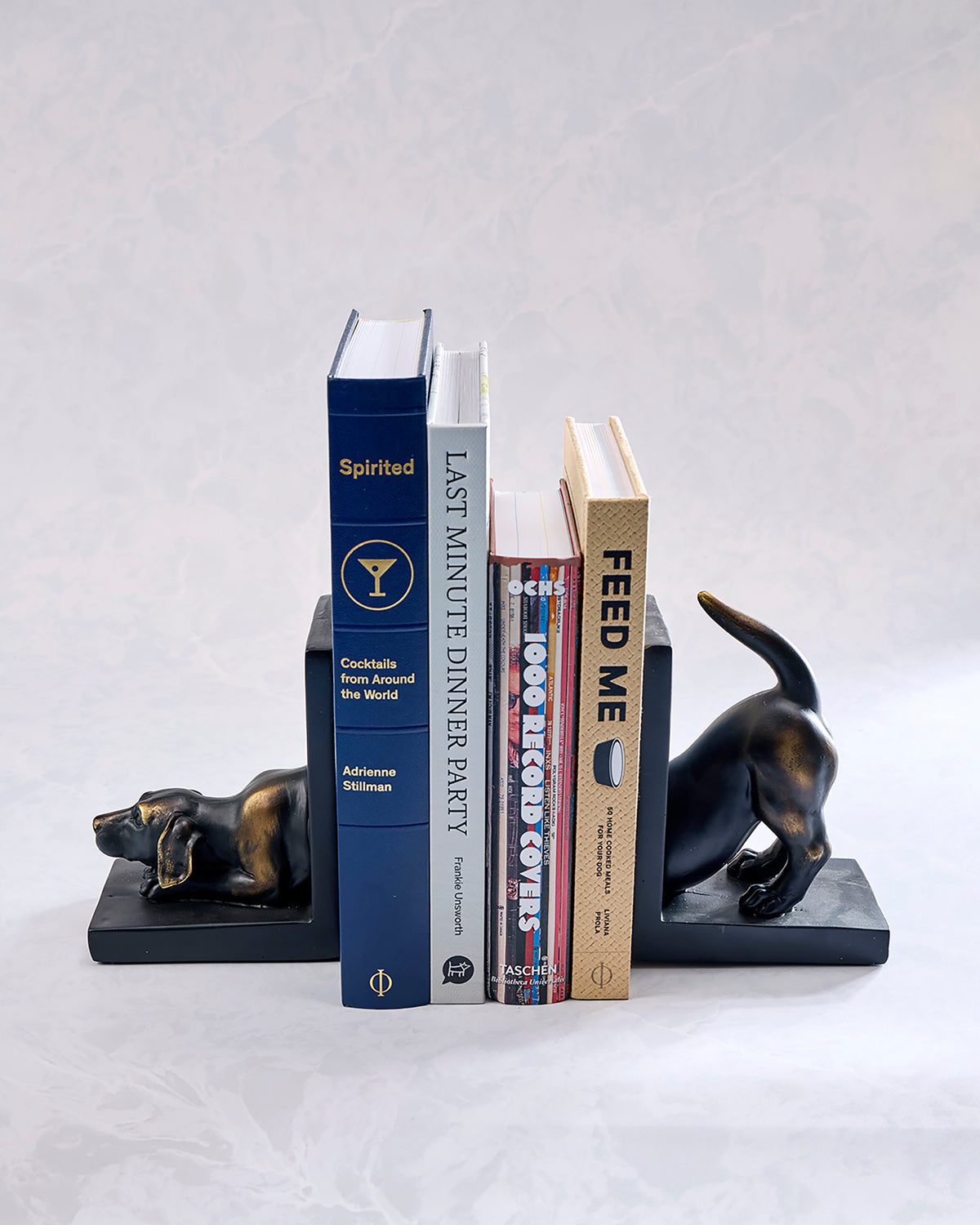 Books arranged between two dog-shaped bookends, one lying down and one standing with its tail raised.