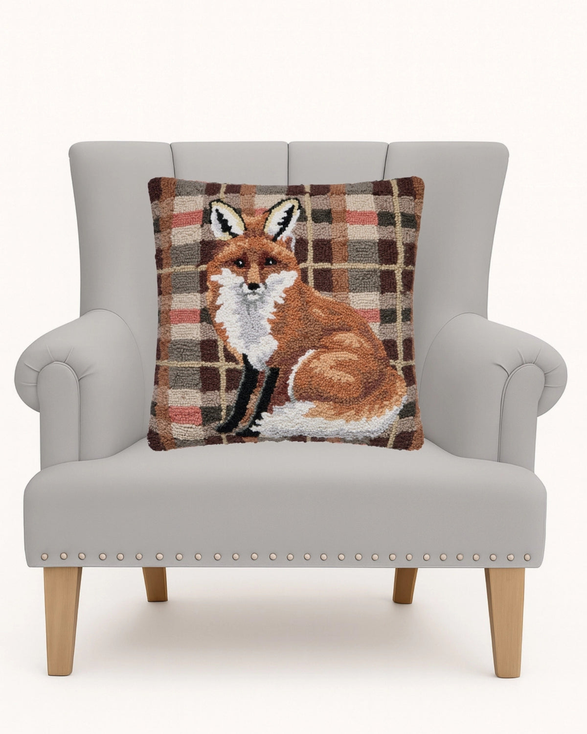 Square hooked fox pillow displayed on a light upholstered armchair.