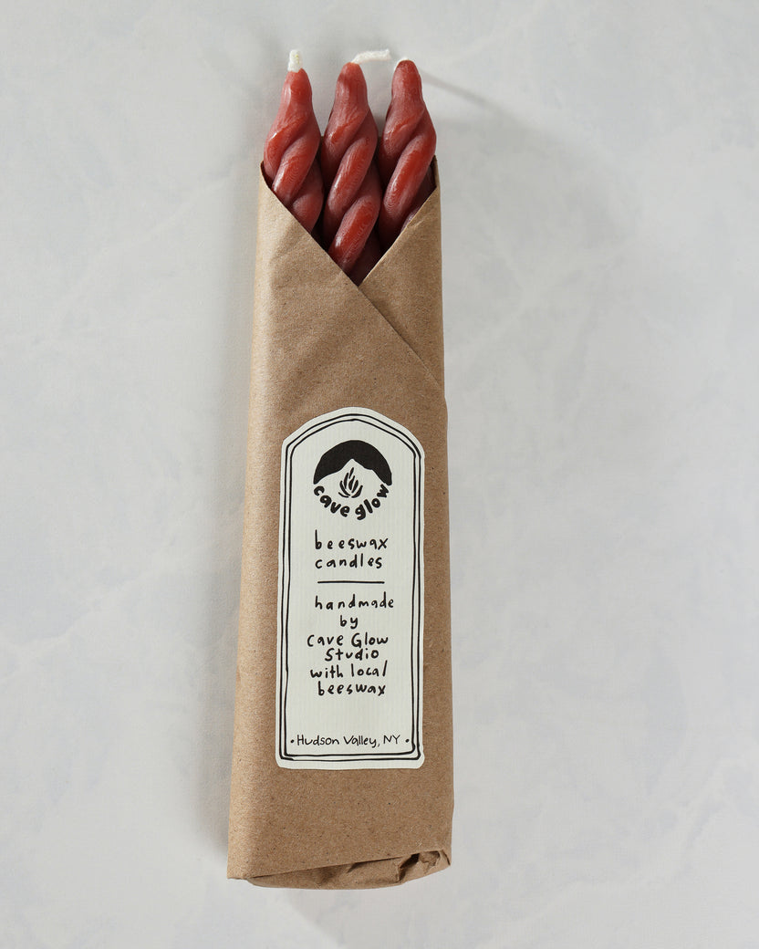 Packaged set of three red spiral candles in a brown paper sleeve with a Cave Glow Studio label.