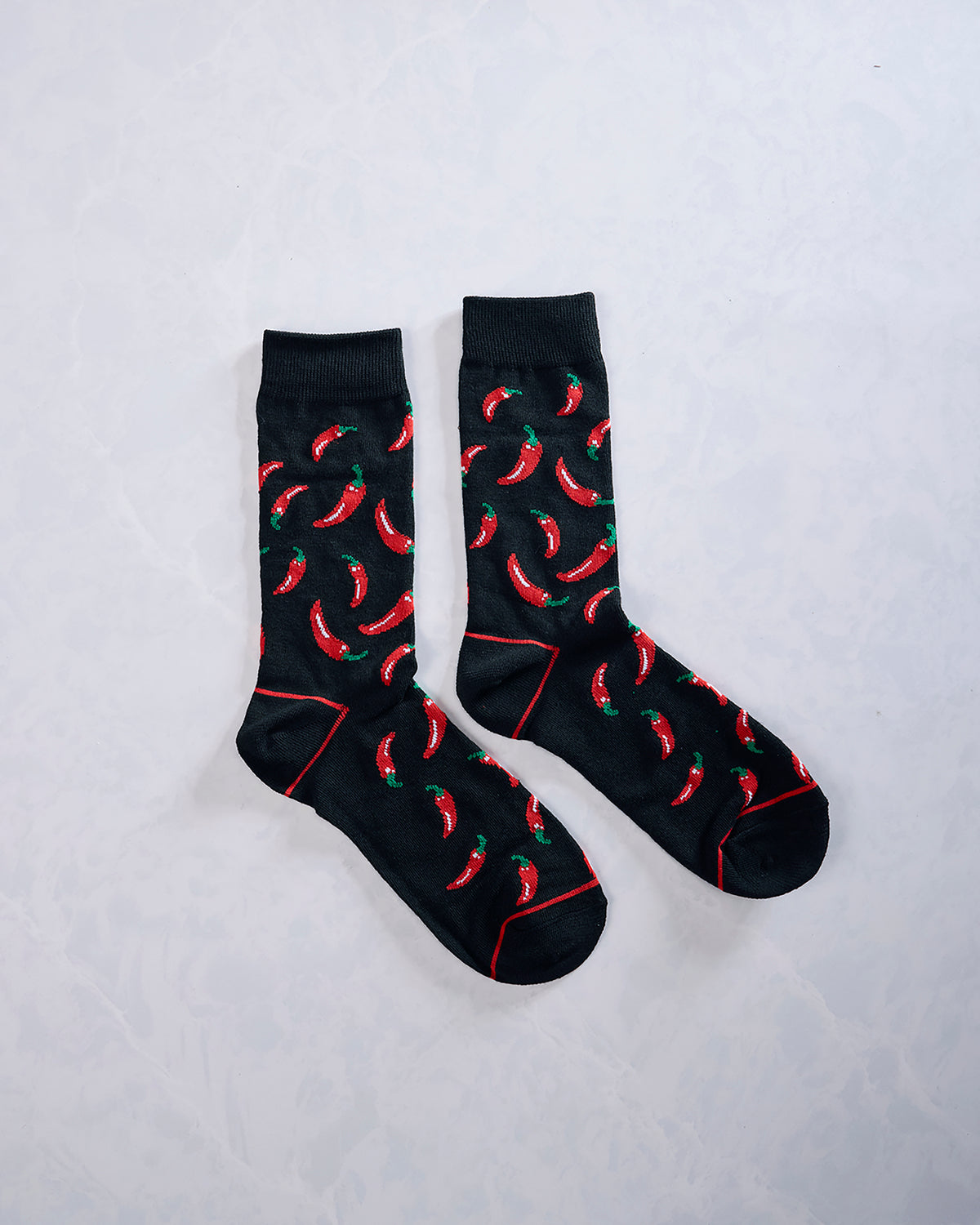 Pair of black socks with repeating red chili pepper designs and red seam details.