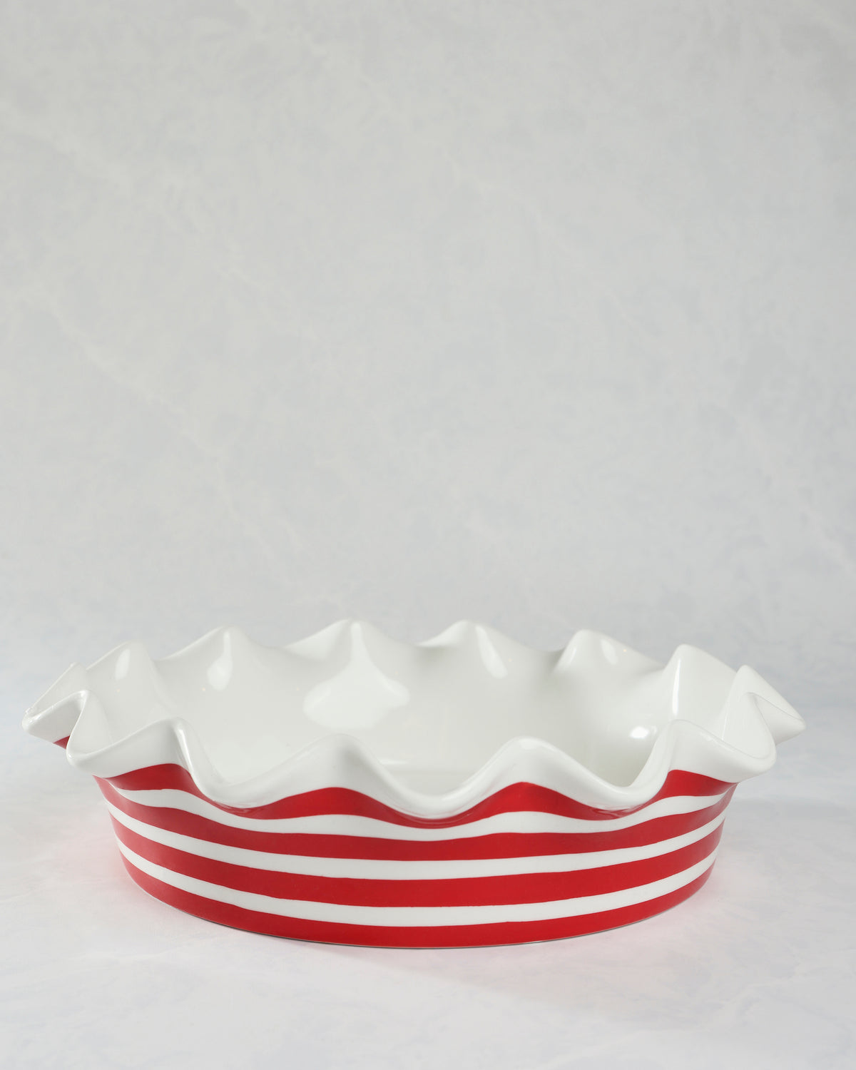 Red-and-white striped ceramic ruffle pie dish shown in a front side view.