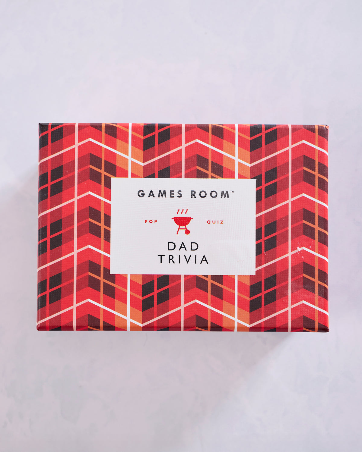 Red patterned box for a Dad Trivia game, with a white label on the front.