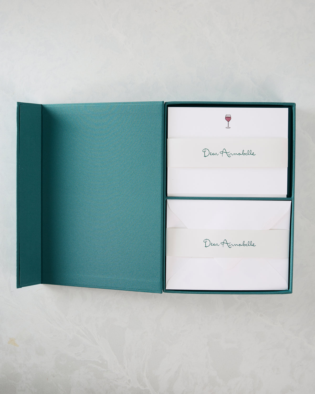 Open teal presentation box containing two sets of white notecards and envelopes, marked “Dear Annabelle” with wine-glass icons.