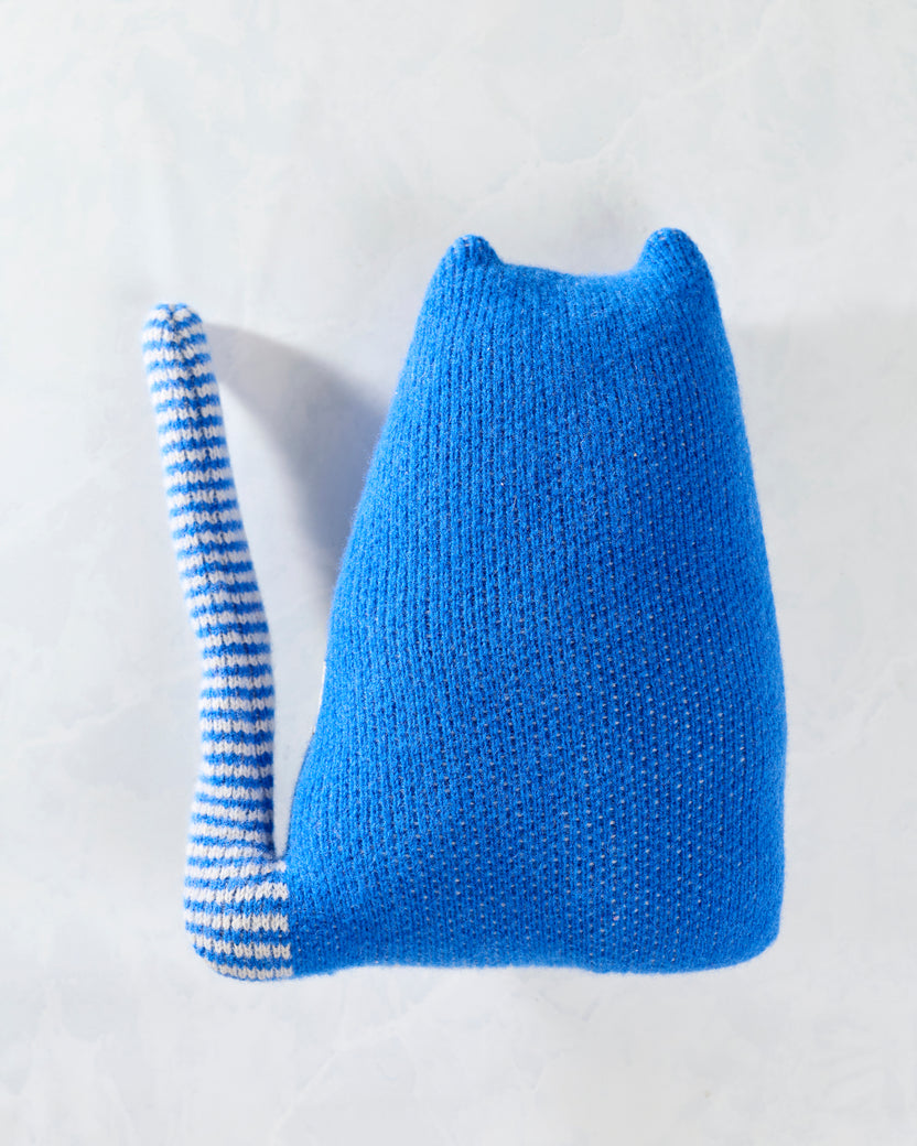 Back view of the blue knitted cat toy, showing its plain blue body and striped tail.