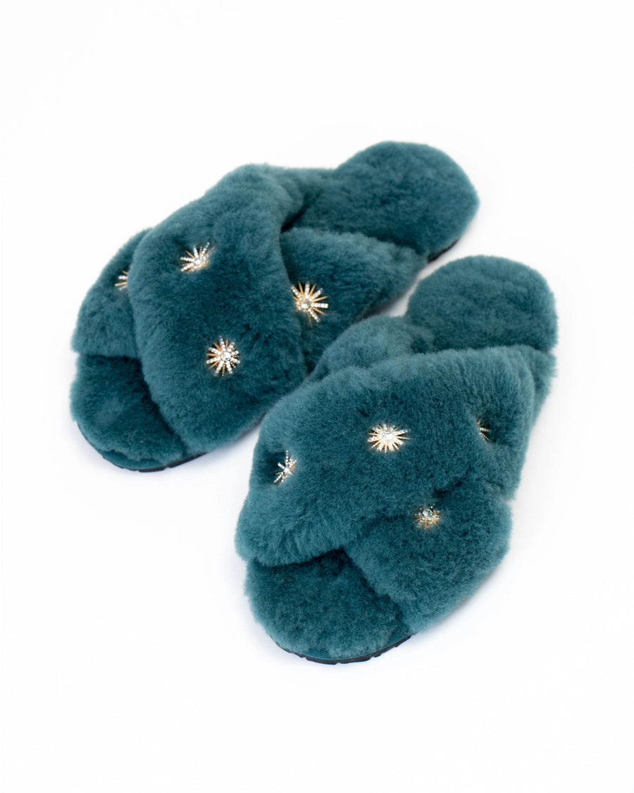 Dusty blue open-toe slippers with crossed plush straps and rhinestone embellishments, shown at an angle.
