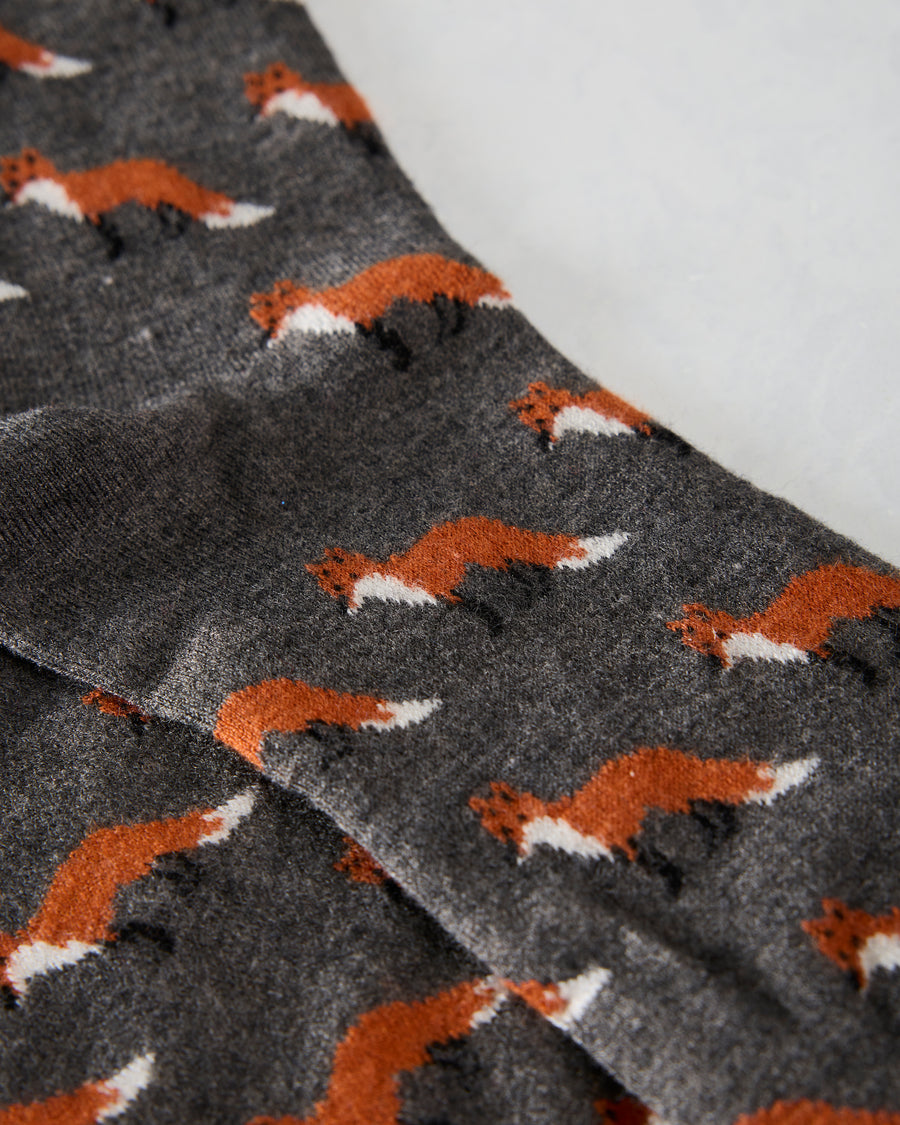 Close-up of grey crew socks with an all-over orange, white, and black fox pattern.